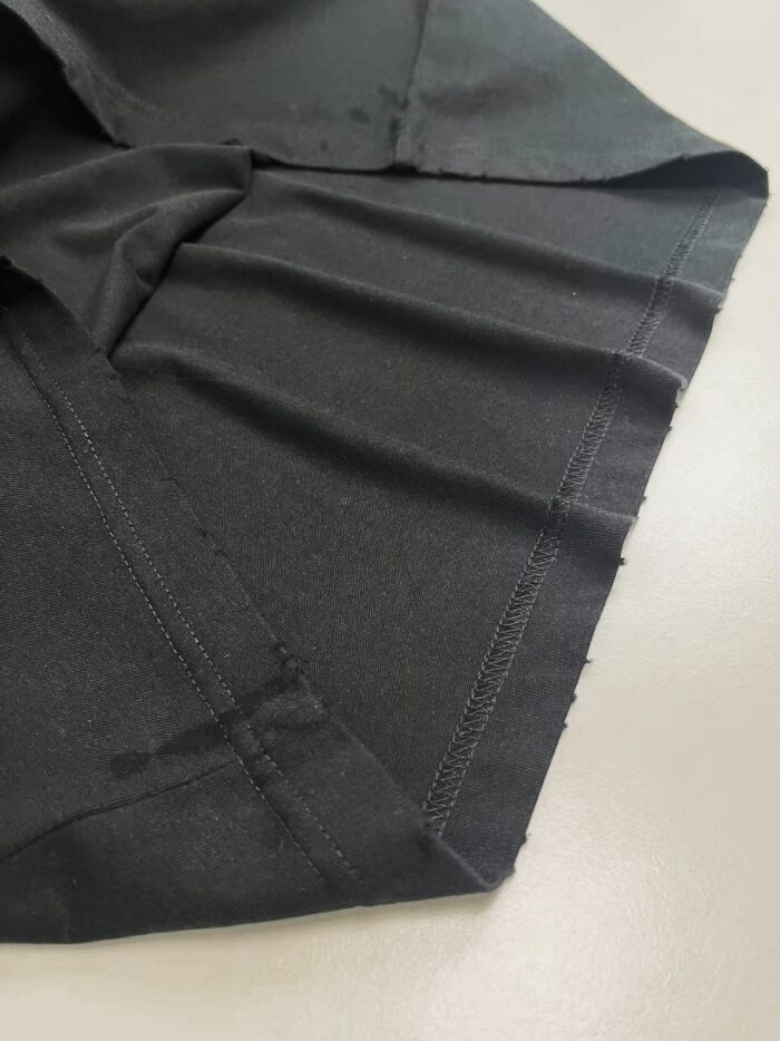 Tessuto nero di alta qualità con cuciture precise e finiture impeccabili, ideale per abbigliamento elegante.
