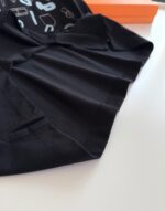 Tessuto nero morbido con dettagli moderni, sfondo arancione vivace, stile streetwear elegante.