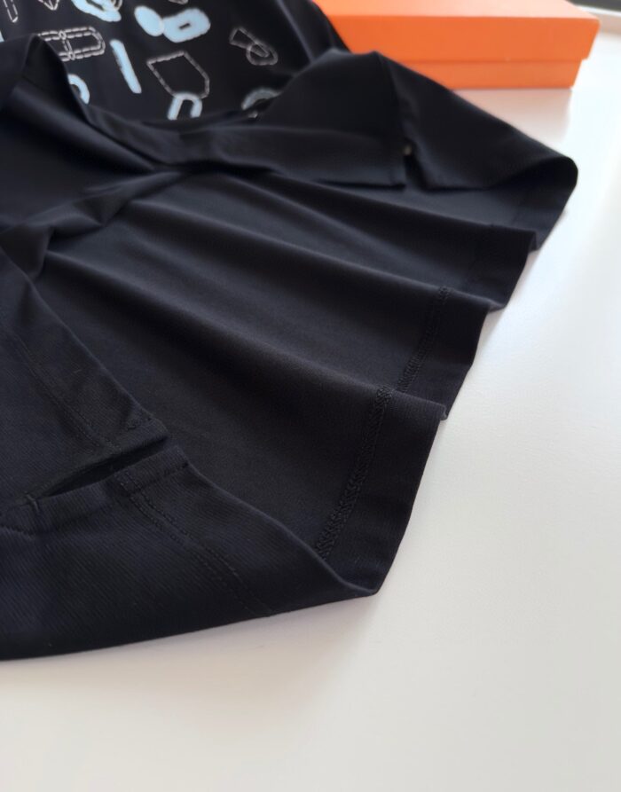 Tessuto nero morbido con dettagli moderni, sfondo arancione vivace, stile streetwear elegante.