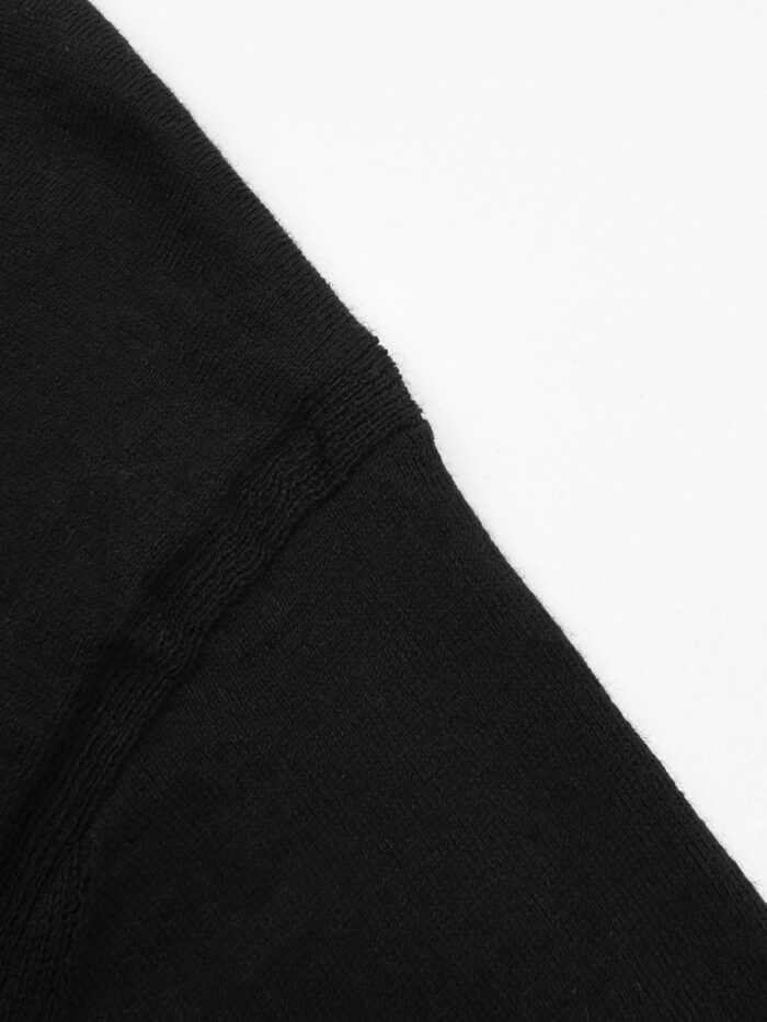 Dettaglio di manica di maglietta nera in cotone di alta qualità, cuciture precise e stile minimalista.