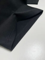 Dettaglio di una maglietta nera con cucitura elegante e tessuto morbido e versatile.