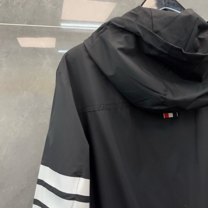 Giacca nera sportiva con cappuccio, strisce bianche e design moderno.