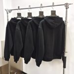 Maglioni neri minimalisti in esposizione su rastrelliera moderna in ambiente elegante.
