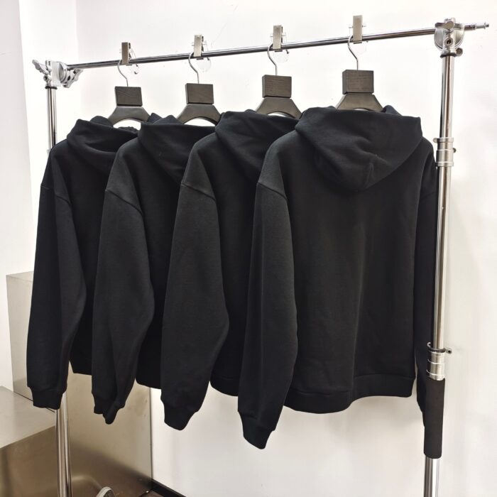 Maglioni neri minimalisti in esposizione su rastrelliera moderna in ambiente elegante.