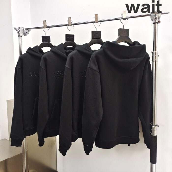 Magliette con cappuccio nere in esposizione con la scritta wait per lattenzione.