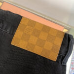 Jeans neri con etichetta checkerboard di lusso, dettaglio di alta moda e stile casual elegante.