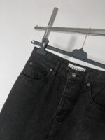 Jeans neri alti di qualità con tasche e dettagli eleganti, appesi a gancio moderno.