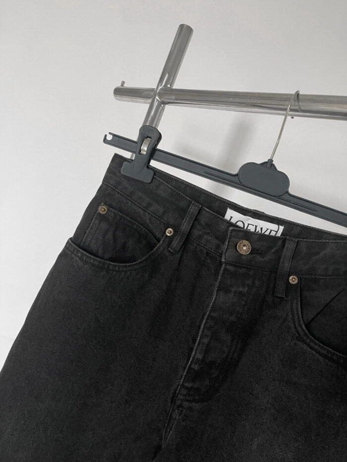 Jeans neri alti di qualità con tasche e dettagli eleganti, appesi a gancio moderno.