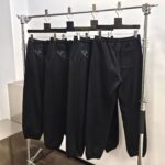 Pantaloni jogger neri sportivi con logo su rack minimalista, ideali per athleisure e casual.