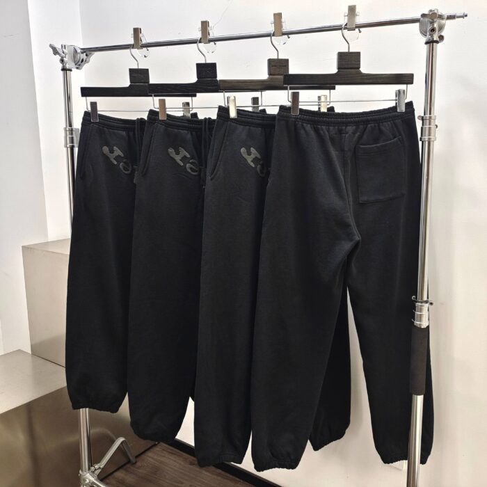 Pantaloni jogger neri sportivi con logo su rack minimalista, ideali per athleisure e casual.