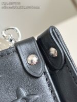 Dettaglio di borsa in pelle nera con chiusure a clips e design elegante.