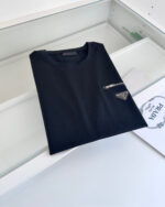 T-shirt nera minimalista con taschino zip e logo triangolare, stile casual ed elegante.