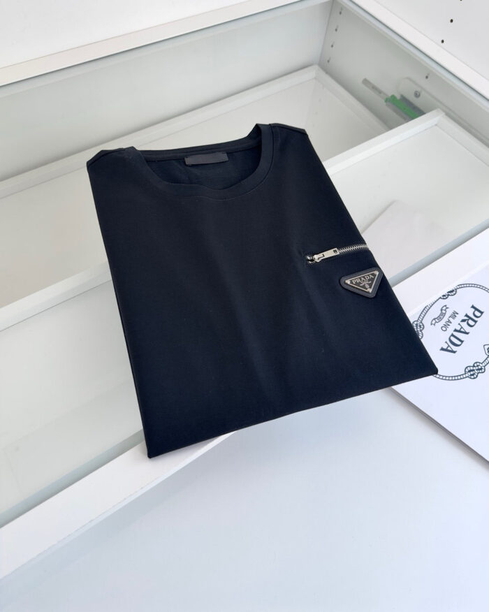 T-shirt nera minimalista con taschino zip e logo triangolare, stile casual ed elegante.