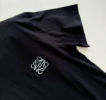 T-shirt nera con logo ricamato, collo leggermente rialzato, stile moderno e versatile.