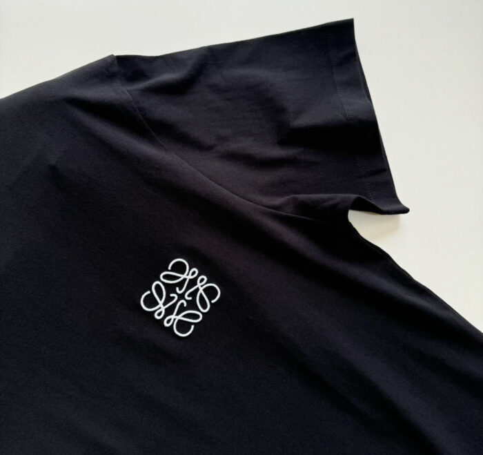 T-shirt nera con logo ricamato, collo leggermente rialzato, stile moderno e versatile.