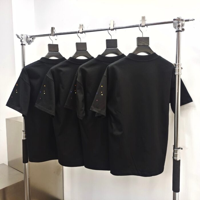 Magliette nere minimaliste su supporto industriale, stile moderno, dettagli curati, perfette per ogni occasione.