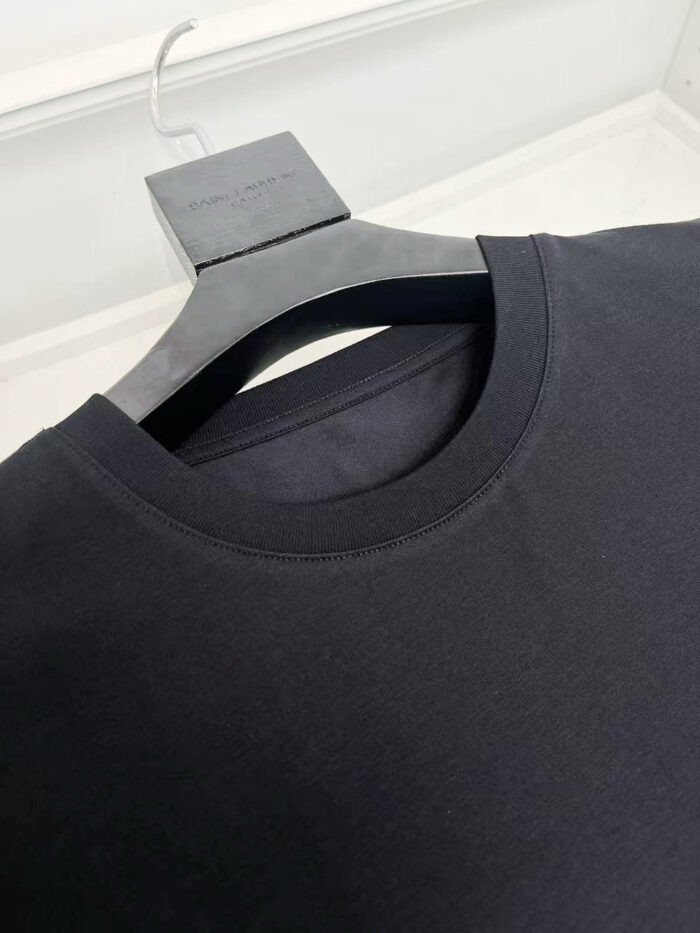 Maglietta nera semplice su appendiabiti minimalista, elegante e di alta qualità.