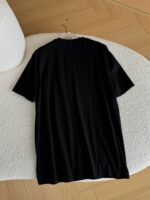 Maglietta nera semplice su superficie bianca, stile minimalista, vestibilità comoda, ideale per look casual.