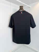 T-shirt nera elegante con dettaglio a strisce rosso-bianco-blu, stile minimalista e versatile.
