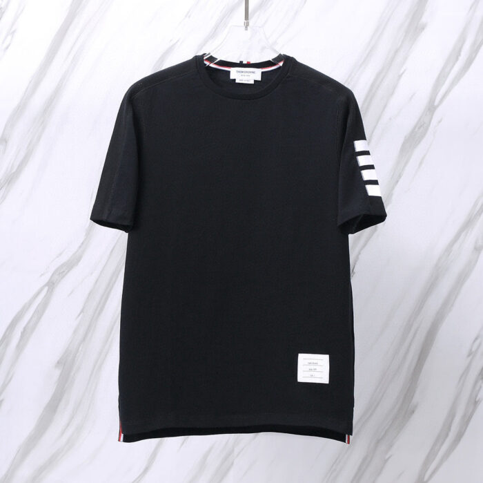 Maglietta nera minimal con dettagli a strisce e patch quadrato, stile sportivo e moderno.