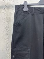 Pantaloni neri moderni con tasche e bottoni metallici, stile elegante e pratico per ogni occasione.