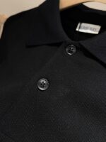Polo nera elegante con tessuto qualità, colletto impeccabile e bottoni lucidi raffinati.