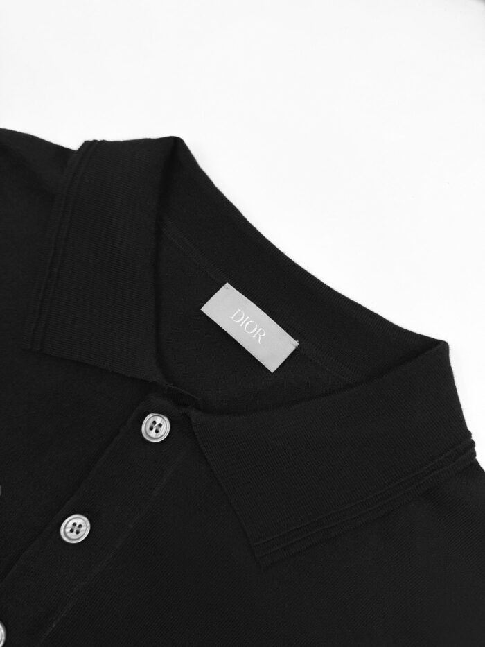 Maglietta polo nera elegante con colletto, bottoni e etichetta minimalista in stile classico.