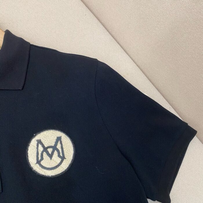 Maglietta polo nera con logo ricamato, stile elegante e versatile, ideale per ogni occasione.