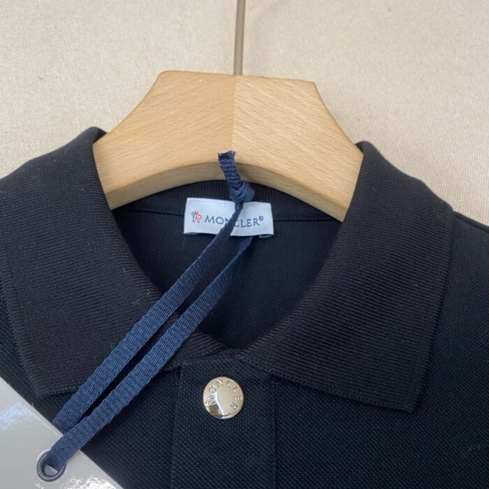 Maglietta polo nera Moller in cotone piqué, dettagli eleganti e nastro navy.