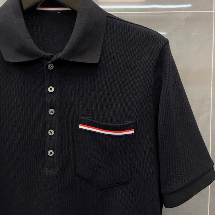 Maglietta polo nera con tasca a strisce rosse e bianche, stile versatile e raffinato.