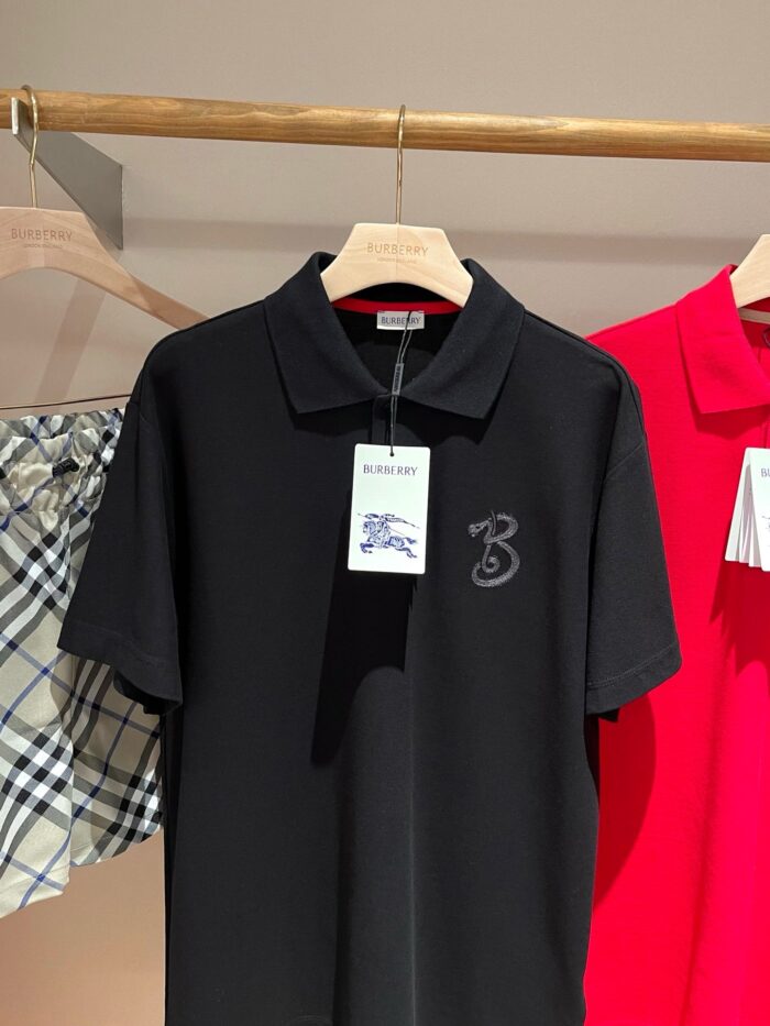 Maglietta polo nera con logo ricamato, accanto a capi colorati e polo rossa vivace.