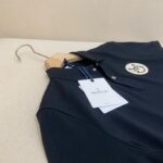 Maglietta polo nera Moncler elegante su gancio in legno, stile raffinato e versatile.