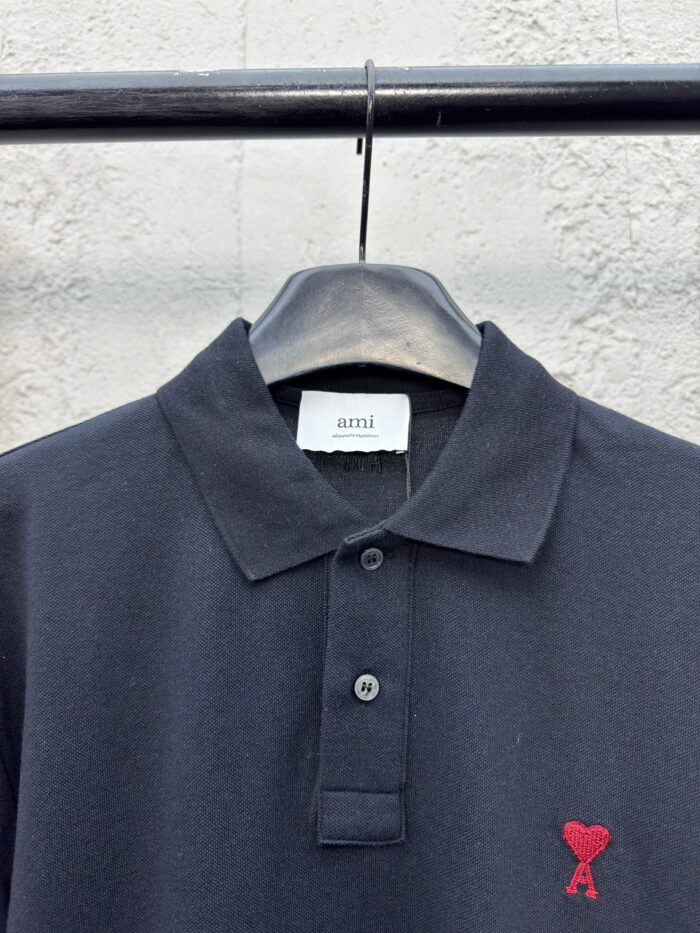 Maglietta polo nera con logo cuore rosso ricamato, stile elegante e versatile per ogni occasione.