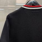 Maglietta polo nera con colletto a strisce rosse e bianche, stile sportivo e casual elegante.