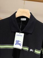 Polo Burberry nera con strisce verdi, logo cavallo, stile elegante casual.