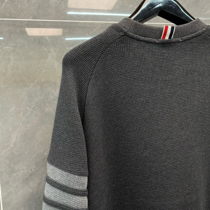 Maglione nero sportivo con strisce colorate, dettagli moderni e design comodo.
