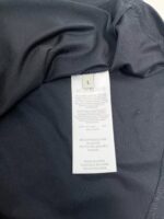 Dettaglio interno di una maglietta nera con etichetta di cura leggibile e tag visibile.