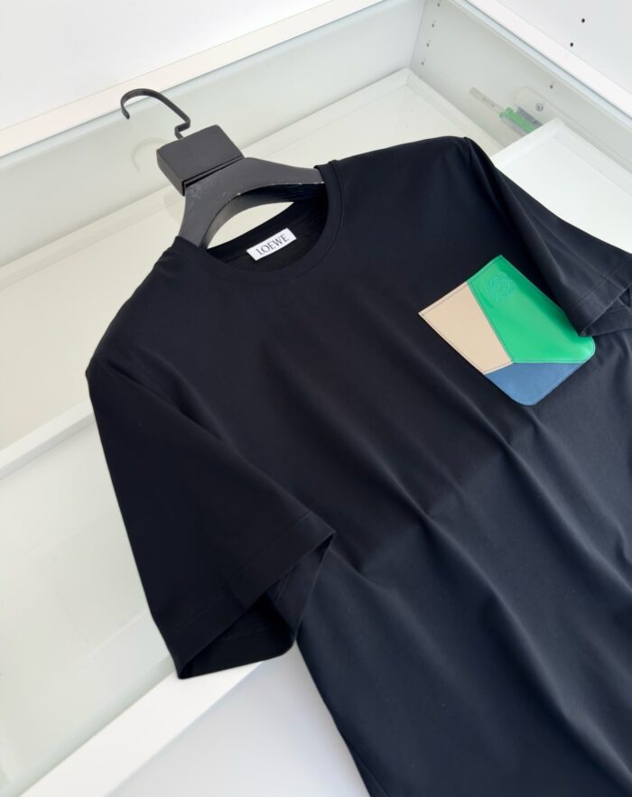 Maglietta nera moderna con tasca colorata a design geometrico, stile casual e versatile.
