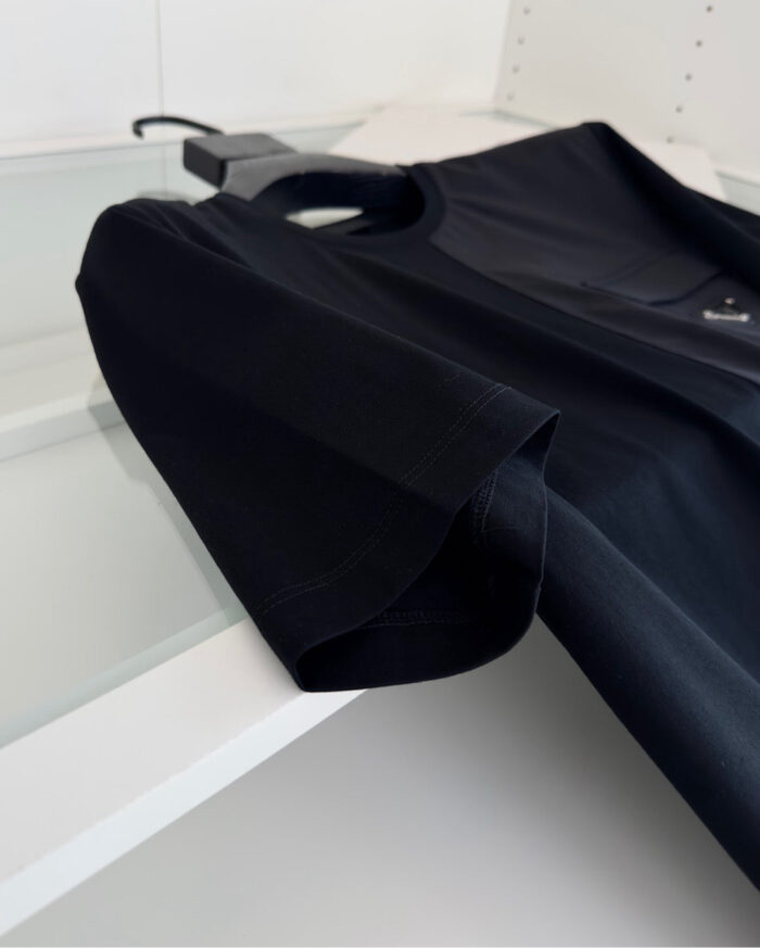 Maglietta nera minimalista con manica a pois e scollo rotondo, elegante e versatile.