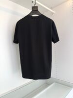 Maglietta nera minimalista a maniche corte, versatile e chic, su sfondo bianco con gruccia nero opaca.