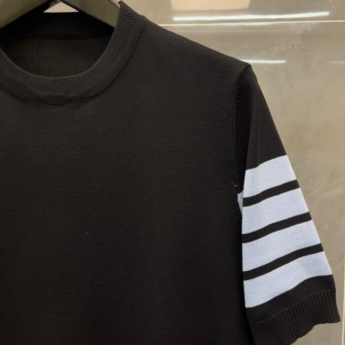 Maglietta corta nera con manica grigia a strisce, stile sporty e moderno.