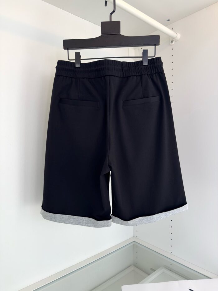 Pantaloncini neri eleganti con tasche, cinturino elasticizzato e risvolti grigi, stile moderno e versatile.