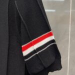Manica a righe rosse e bianche su maglione nero casual e raffinato.