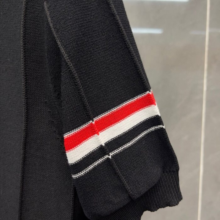 Manica a righe rosse e bianche su maglione nero casual e raffinato.