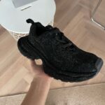 Scarpa da ginnastica nera con dettagli riflettenti, comoda e moderna per sport e uso quotidiano.