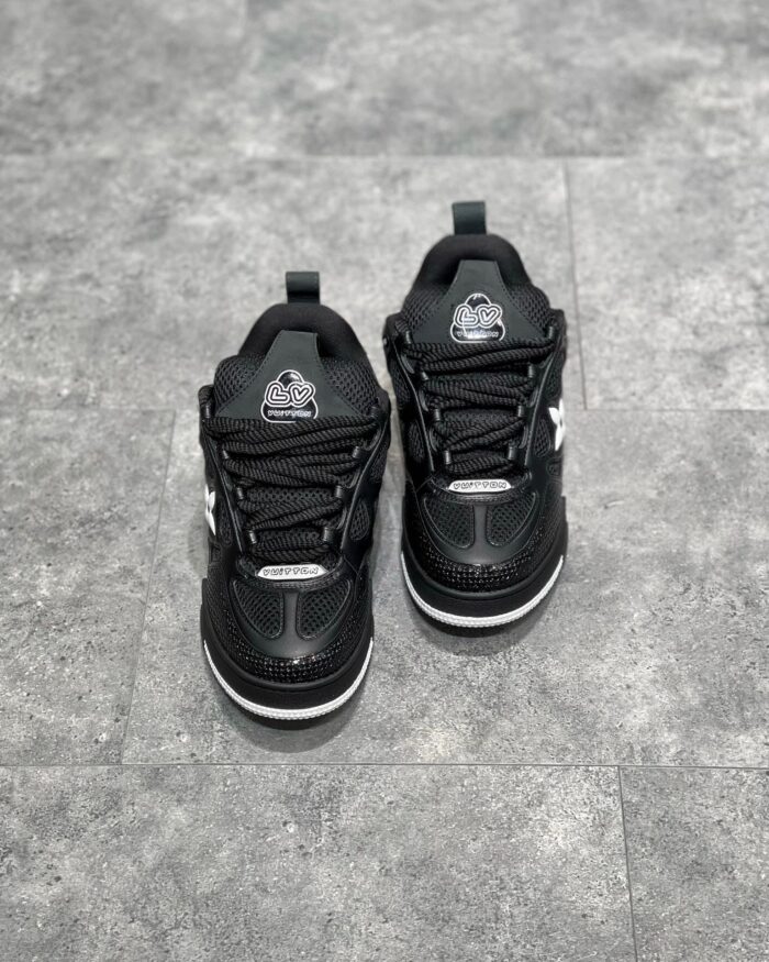 Sneakers nere sportive moderne con logo circolare, su pavimento grigio testurizzato.