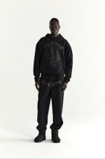 Look streetwear nero con hoodie oversized, joggers e stivali per uno stile urbano e moderno.