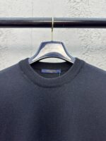 Maglione nero casual su gancio, sfondo industriale, stile minimalista e semplice.