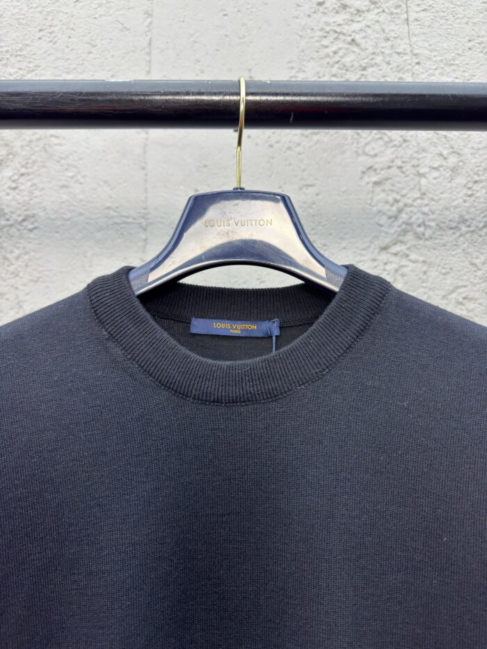 Maglione nero casual su gancio, sfondo industriale, stile minimalista e semplice.