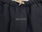 Pantaloni jogger neri con elastico, cordino beige e dettaglio minimalista elegante.